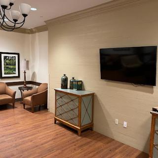 A cozy living room area featuring comfortable chairs, a wall-mounted TV, and stylish furniture.