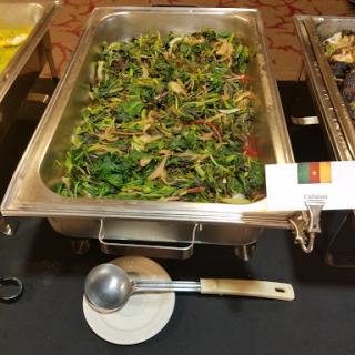 A tray of vibrant, fresh vegetable dish from Cameroon, showcasing a mix of leafy greens.