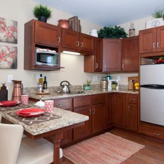 A modern kitchen featuring wooden cabinets, a countertop with dining space, and various appliances.