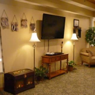 A cozy living room setup with a wall-mounted TV, lamps, and decorative elements.