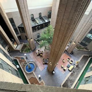 A view of a contemporary indoor courtyard featuring a fountain surrounded by seating areas and greenery.