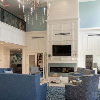 A modern living room with elegant furnishings, featuring a grand chandelier and a cozy fireplace.
