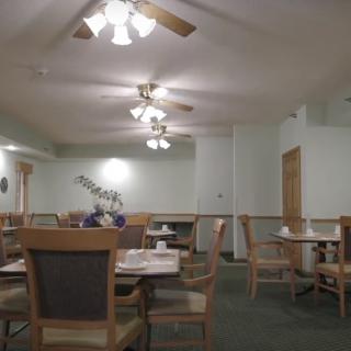 An empty dining area with tables and chairs, featuring ceiling fans and simple decor.