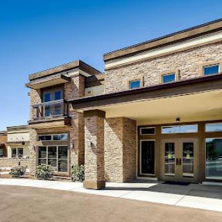 A modern commercial building with brick exterior and large glass windows under a clear blue sky.
