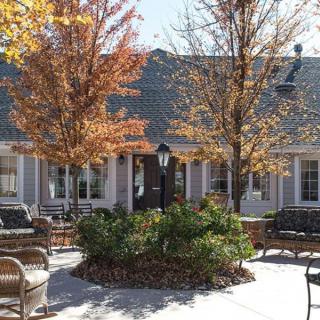 A cozy outdoor patio area with seating and trees in front of a building.