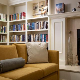 A cozy living room with a bookshelf filled with books, a yellow couch, and a fireplace.