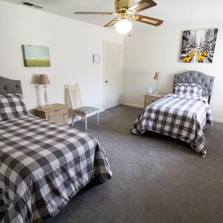 A cozy bedroom featuring two twin beds with checkered bedding, adorned with wall art and a ceiling fan.