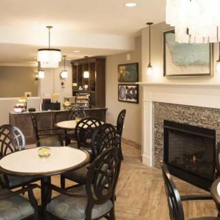A modern dining area with round tables, cushioned chairs, and a cozy fireplace.