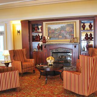 A cozy living room with a fireplace, decorated in a traditional style with striped armchairs.