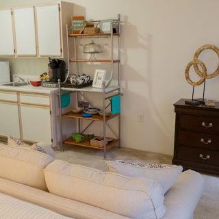 A cozy apartment interior featuring a small kitchen area with shelves and decorative items.