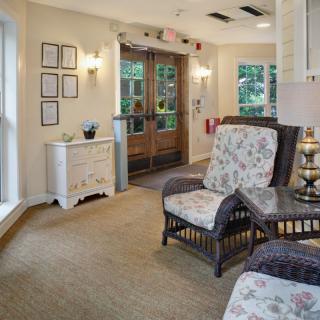 A cozy lobby area with wicker chairs and floral cushions near an entrance.