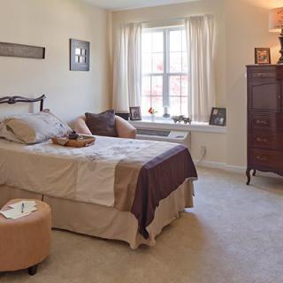 A cozy bedroom with a bed, window with curtains, and classic furniture.