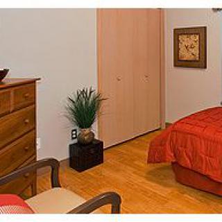 Cozy bedroom with a dresser and bed, featuring warm tones and simple decor.