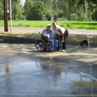 A joyful moment shared outdoors as two individuals enjoy a sunny day near a splash of water.