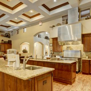 A spacious and modern kitchen with granite countertops, stainless steel appliances, and elegant wood cabinetry.