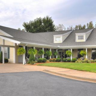 A spacious house with a large porch and well-maintained landscaping.