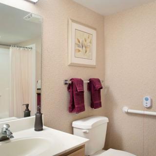 A clean and well-organized bathroom featuring a large mirror, sink, toilet, and neatly hung towels.