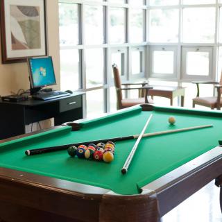 A cozy game room featuring a pool table with cue sticks and billiard balls ready for play.