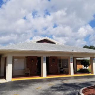 A modern residential building with a spacious entrance and a driveway under a partly cloudy sky.