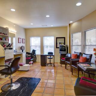 A bright and cozy salon interior featuring a hairdressing station and a comfortable waiting area with plush chairs.