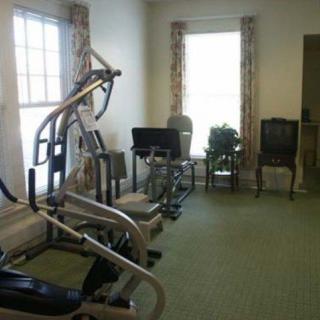 A home gym with exercise equipment and chairs in a bright room.
