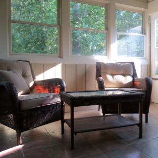 A cozy sunroom with two chairs and a table, bathed in natural light.
