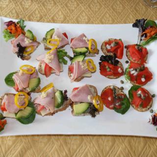 A platter of assorted sandwiches featuring ham, vegetables, and garnishes.