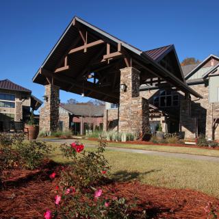 A beautiful building entrance with stone architecture and landscaped garden featuring roses.
