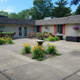 A beautiful patio area with a central fountain, surrounded by flowers and greenery.