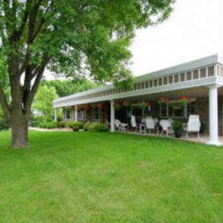 A modern house with a spacious porch overlooking a lush green lawn and trees.