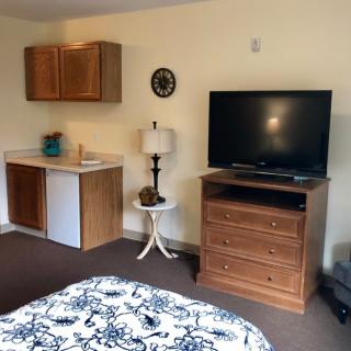 A cozy hotel room with a television, mini fridge, and wooden furniture.