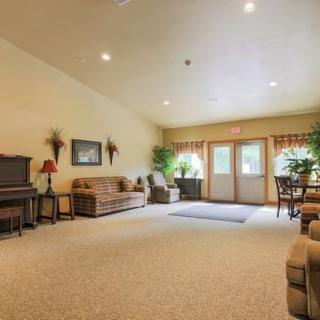 A spacious living room with comfortable seating, a piano, and natural light.