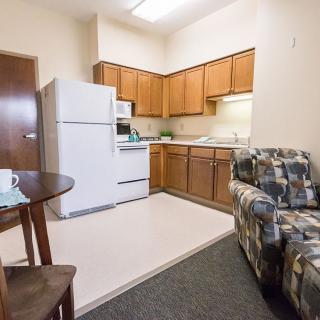 A cozy apartment kitchen and living area with wooden cabinets and a comfortable sofa.