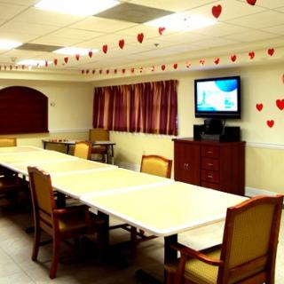 A decorated meeting room with a long conference table, chairs, and a television.