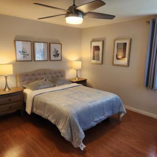 A cozy bedroom featuring a neatly made bed, decorative lamps, and framed artwork on the walls.