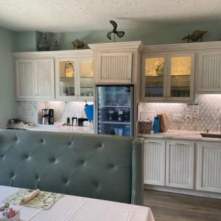 A modern kitchen with white cabinets, a refrigerator, and ambient lighting.