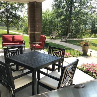 A serene patio with comfortable seating surrounded by lush greenery.