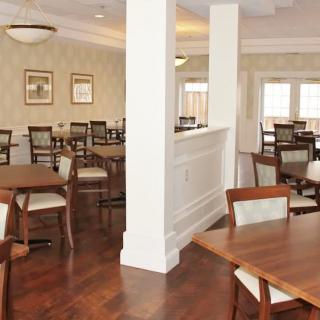 A spacious dining area with wooden tables and chairs, featuring elegant interior design.