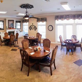 A well-decorated dining room with multiple round tables and chairs, featuring ample natural light and stylish lighting fixtures.