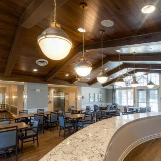 A modern dining room with elegant lighting and wooden ceiling.