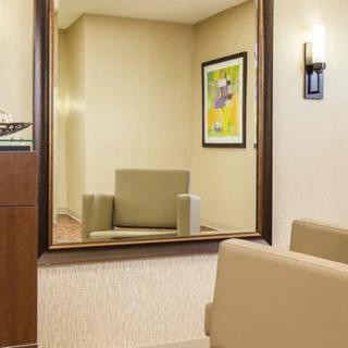 A modern lobby with a mirror reflecting a sofa and artwork on the wall.