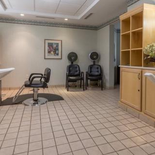 An empty hair salon with styling chair, dryer chairs, and tidy cabinets.