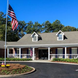 A house with a front porch and an American flag in the front yard.