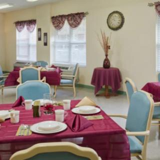 A neatly arranged dining room with tables set for a meal, featuring red tablecloths and blue chairs.