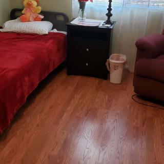 A cozy bedroom with a bed, nightstand, and armchair on a wooden floor.