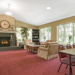 A cozy living room with a fireplace, plush furniture, and large windows.