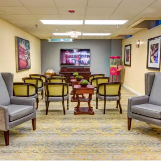A cozy interior room resembling a home theater setup, featuring arranged chairs facing a television, with decorative elements and a popcorn machine on the side.