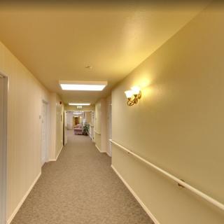 A well-lit corridor with carpeted flooring and handrails along the walls.