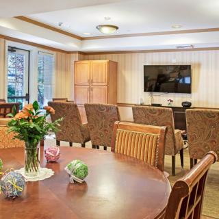 A cozy living room featuring a television, wooden furniture, and a table adorned with flowers.
