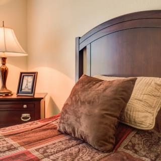 A cozy bedroom with a wooden headboard and a neatly arranged nightstand.